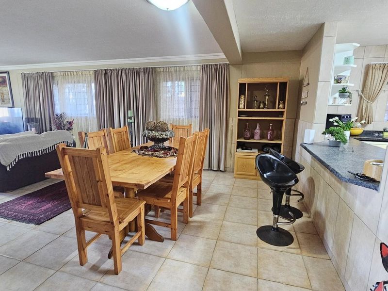 Open-plan living and dining area featuring tiled flooring, a breakfast counter, and direct flow between the kitchen and lounge space.