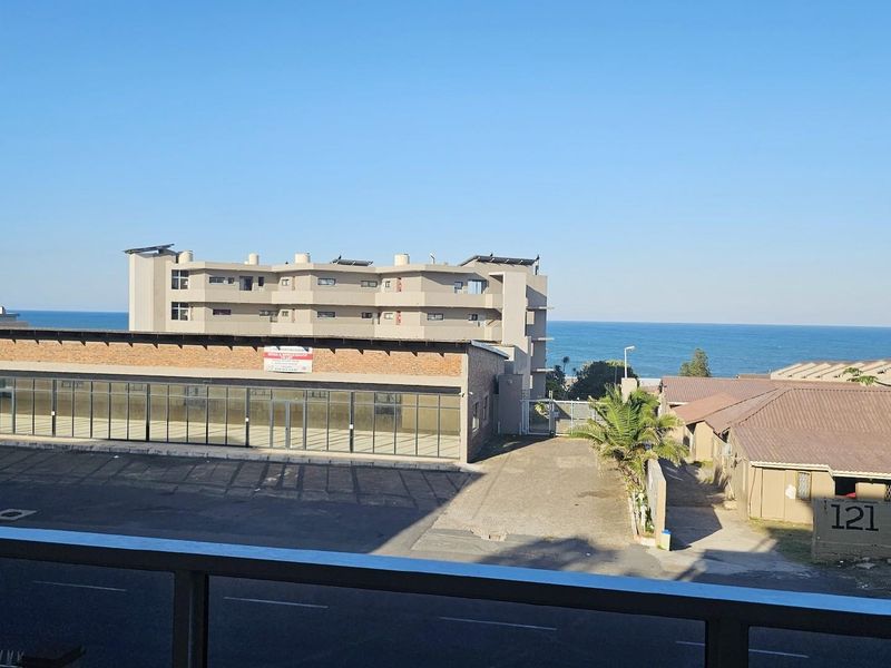 Elevated view overlooking the surrounding neighbourhood, commercial building, and coastal horizon.