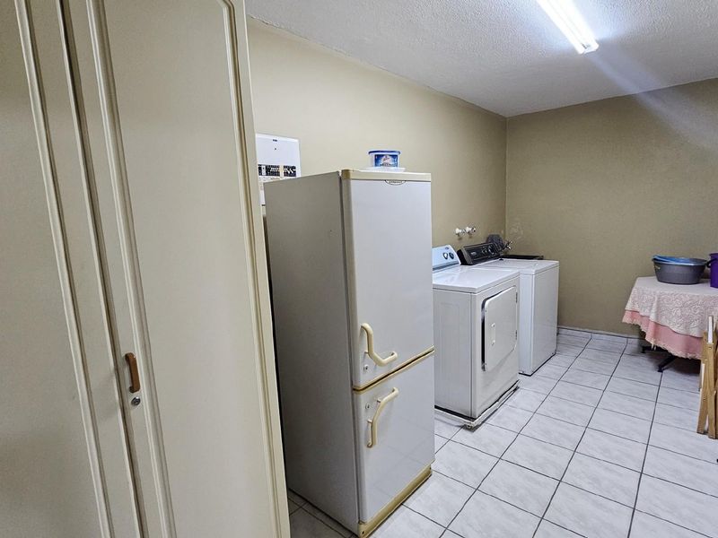 A functional laundry room featuring tiled flooring, built-in cabinetry, and dedicated space for laundry appliances.