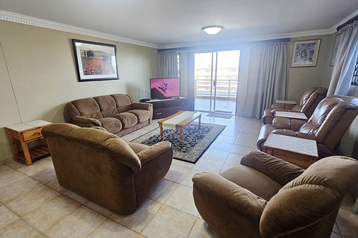 Spacious living room featuring tiled flooring, crown molding, and large sliding glass doors providing access to an outdoor balcony area.