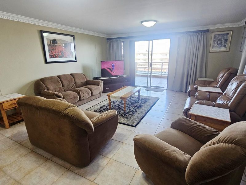 Spacious living room featuring tiled flooring, crown molding, and large sliding glass doors providing access to an outdoor balcony area.
