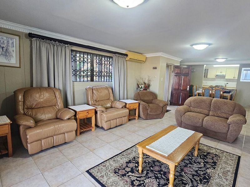 Open-plan living and dining area featuring tiled flooring, crown molding, and a split-system air conditioning unit.