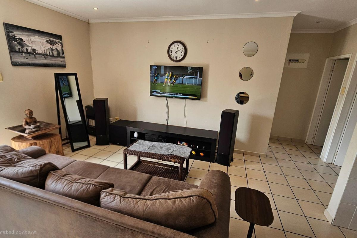A living room featuring tiled flooring, recessed ceiling lighting, and a wall-mounted television setup.