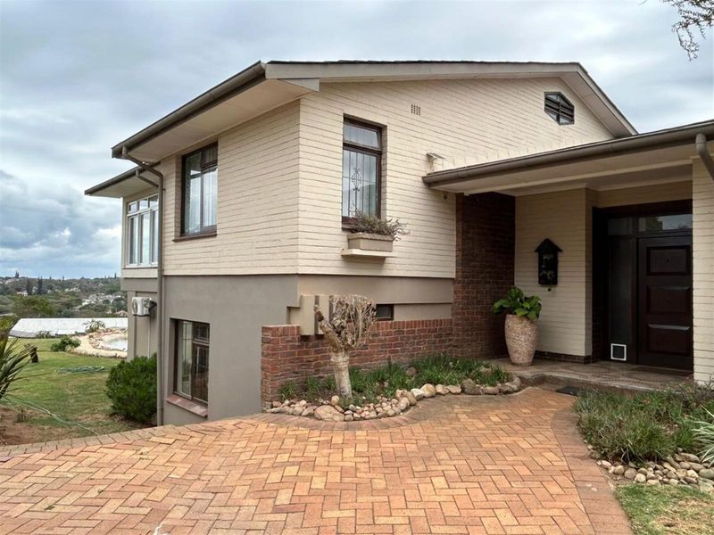 Front exterior view of a multi-level house featuring brick and painted masonry facade, paved driveway, and covered entrance.