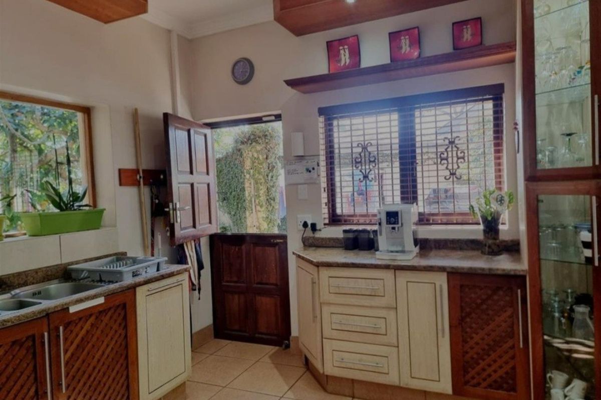 A functional kitchen featuring wooden cabinetry, stone-look countertops, tiled flooring, and a stable-style door providing direct access to the exterior.