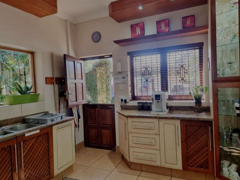 A functional kitchen featuring wooden cabinetry, stone-look countertops, tiled flooring, and a stable-style door providing direct access to the exterior.
