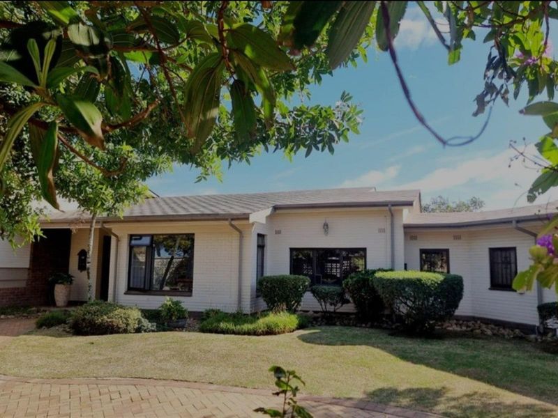 A well-maintained single-story residential home featuring a painted brick facade, tiled roof, and established front garden with paved driveway.