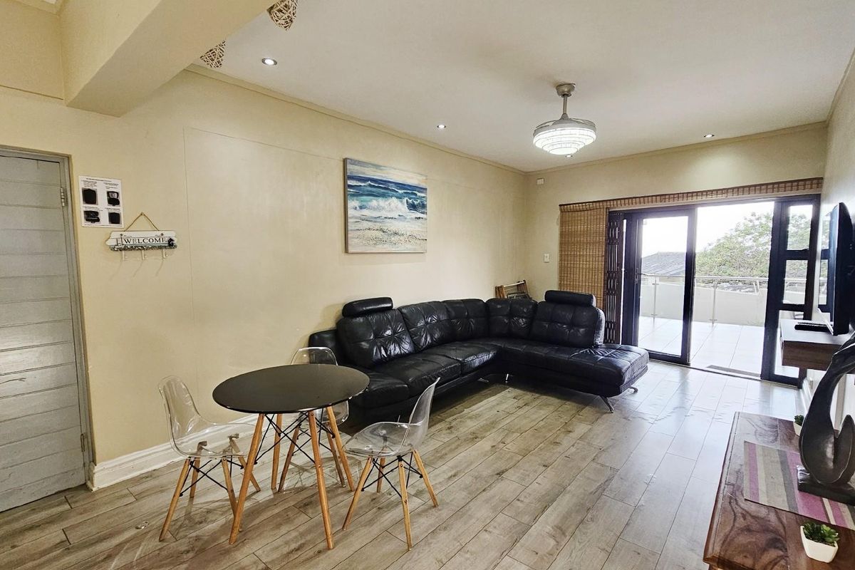Spacious living area featuring wood-look flooring, recessed ceiling lighting, and large sliding glass doors providing access to an outdoor balcony.