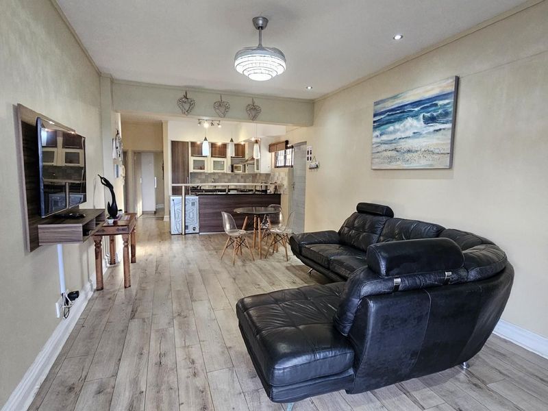 Open-plan living and kitchen area featuring wood-look flooring, recessed lighting, and a breakfast bar counter.
