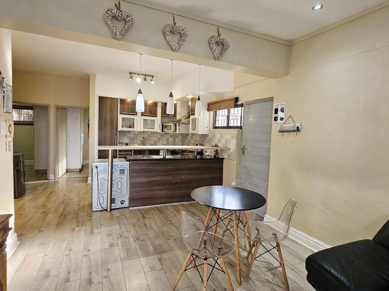Open-plan living area featuring a kitchen with dark wood cabinetry, breakfast bar, and wood-look flooring, seamlessly connecting to the dining and living space.
