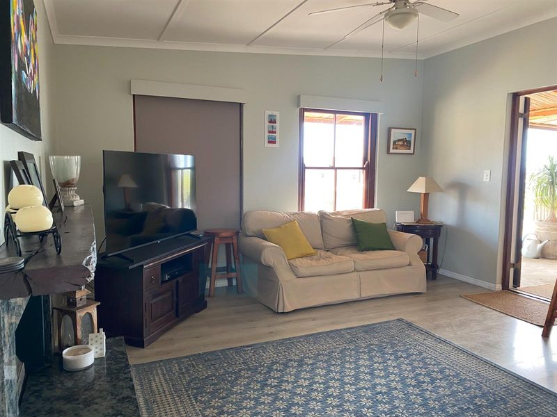 A comfortable living room featuring light-toned flooring, a ceiling fan, and direct access to an outdoor patio area.