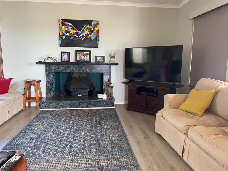 A living room featuring a stone-clad fireplace with a hearth and light-toned laminate flooring.