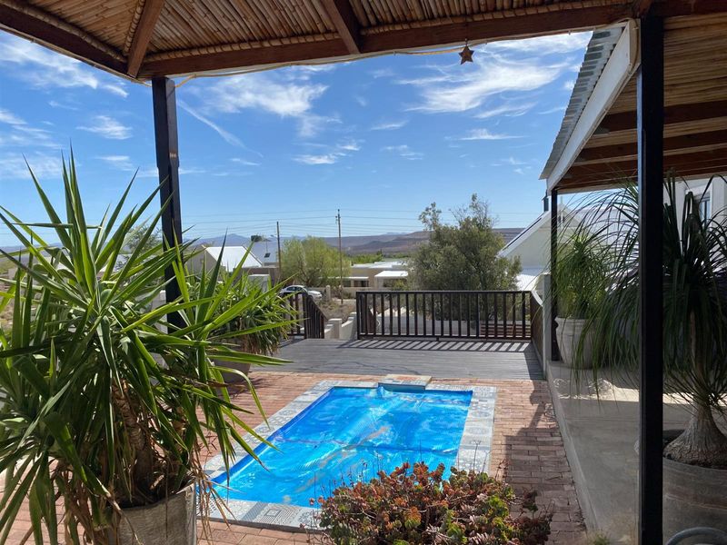 Covered patio area overlooking a small plunge pool with a wooden deck and scenic mountain views.