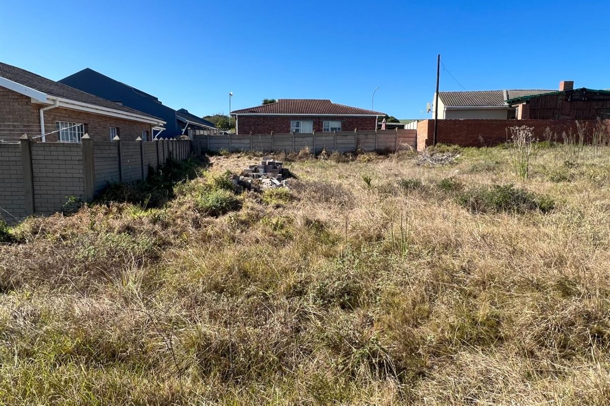 A vacant residential plot featuring perimeter boundary walls and established surrounding residential properties, offering a clear space for future development.