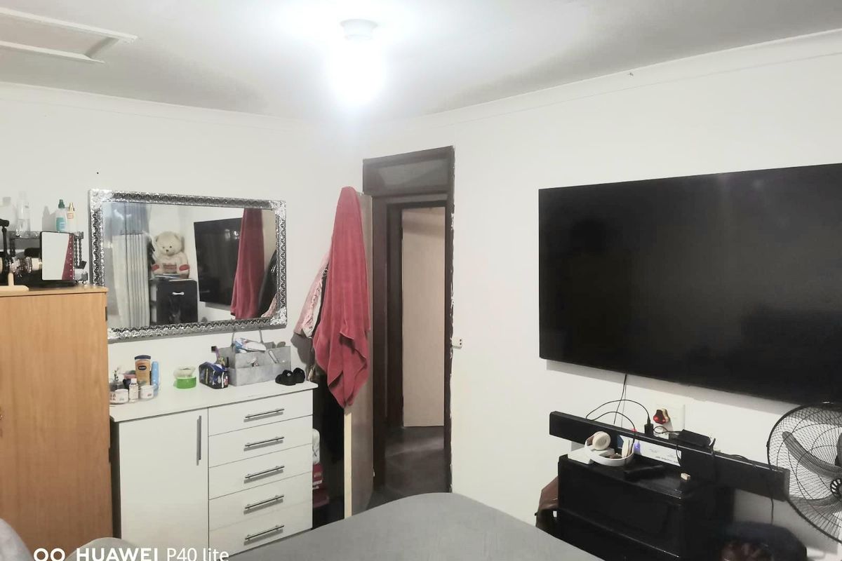 A bedroom featuring a wall-mounted television, ceiling light fixture, and standard door access.