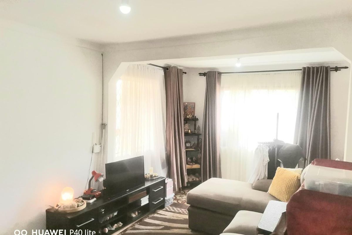 A living room featuring large windows with curtains, providing natural light and a view of the exterior.