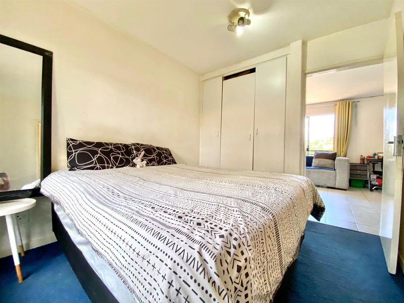 A functional bedroom featuring a built-in wardrobe and direct access to an adjacent living area.