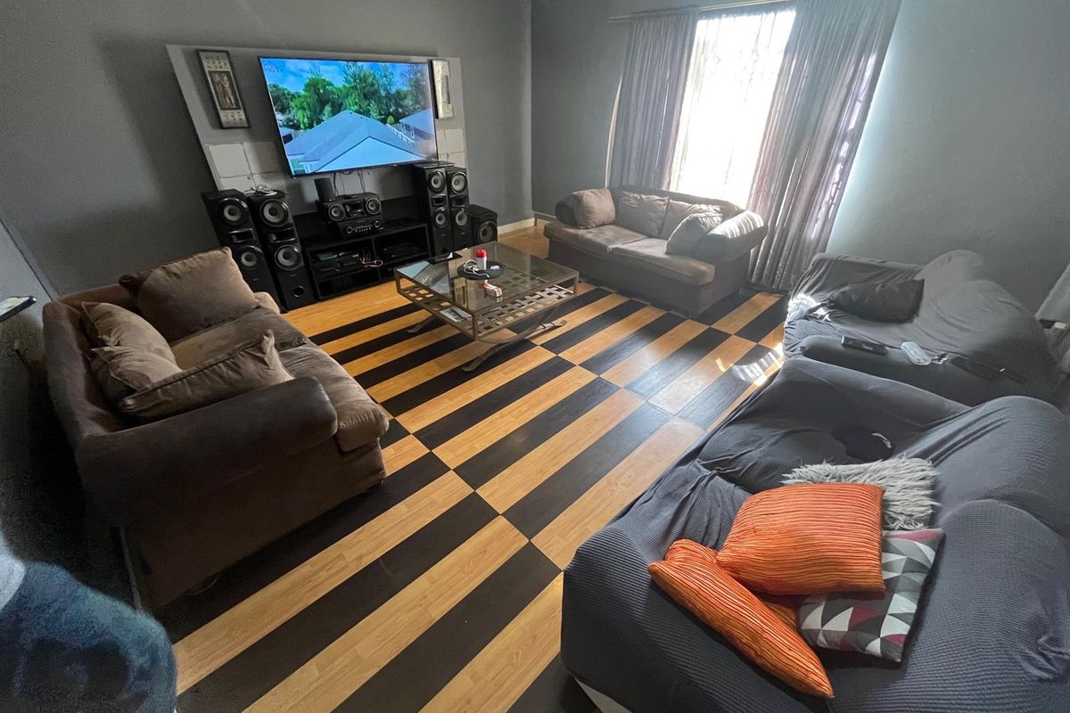 A living room featuring a distinctive two-tone checkered laminate floor and dark grey painted walls with window curtain treatments.