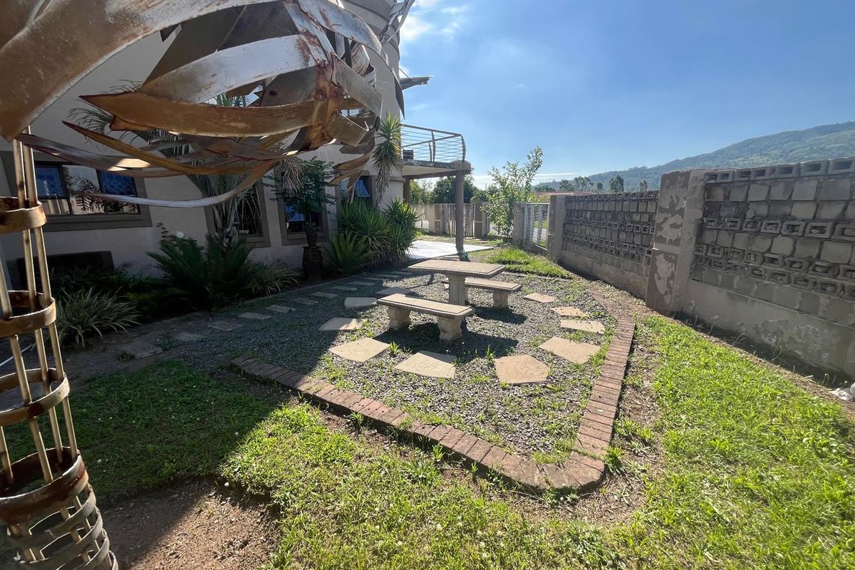 Rear garden area featuring a gravel patio with stone pavers, brick edging, and a concrete block boundary wall.