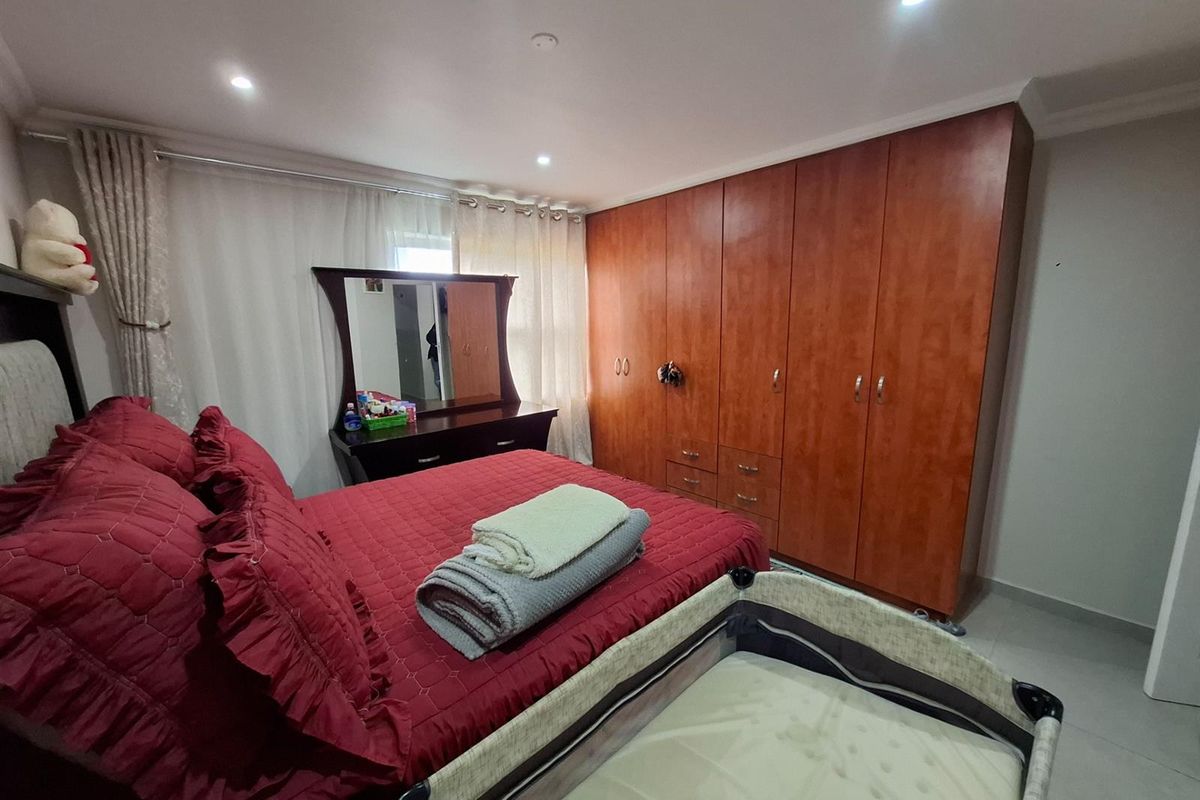A well-lit bedroom featuring built-in wooden cabinetry and tiled flooring, providing ample storage space and a functional layout.