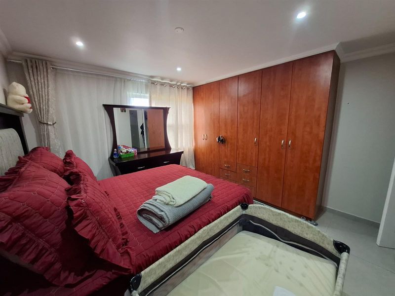 A well-lit bedroom featuring built-in wooden cabinetry and tiled flooring, providing ample storage space and a functional layout.