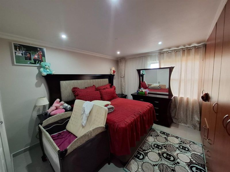A well-maintained bedroom featuring built-in wooden cabinetry, recessed ceiling lighting, and tiled flooring.