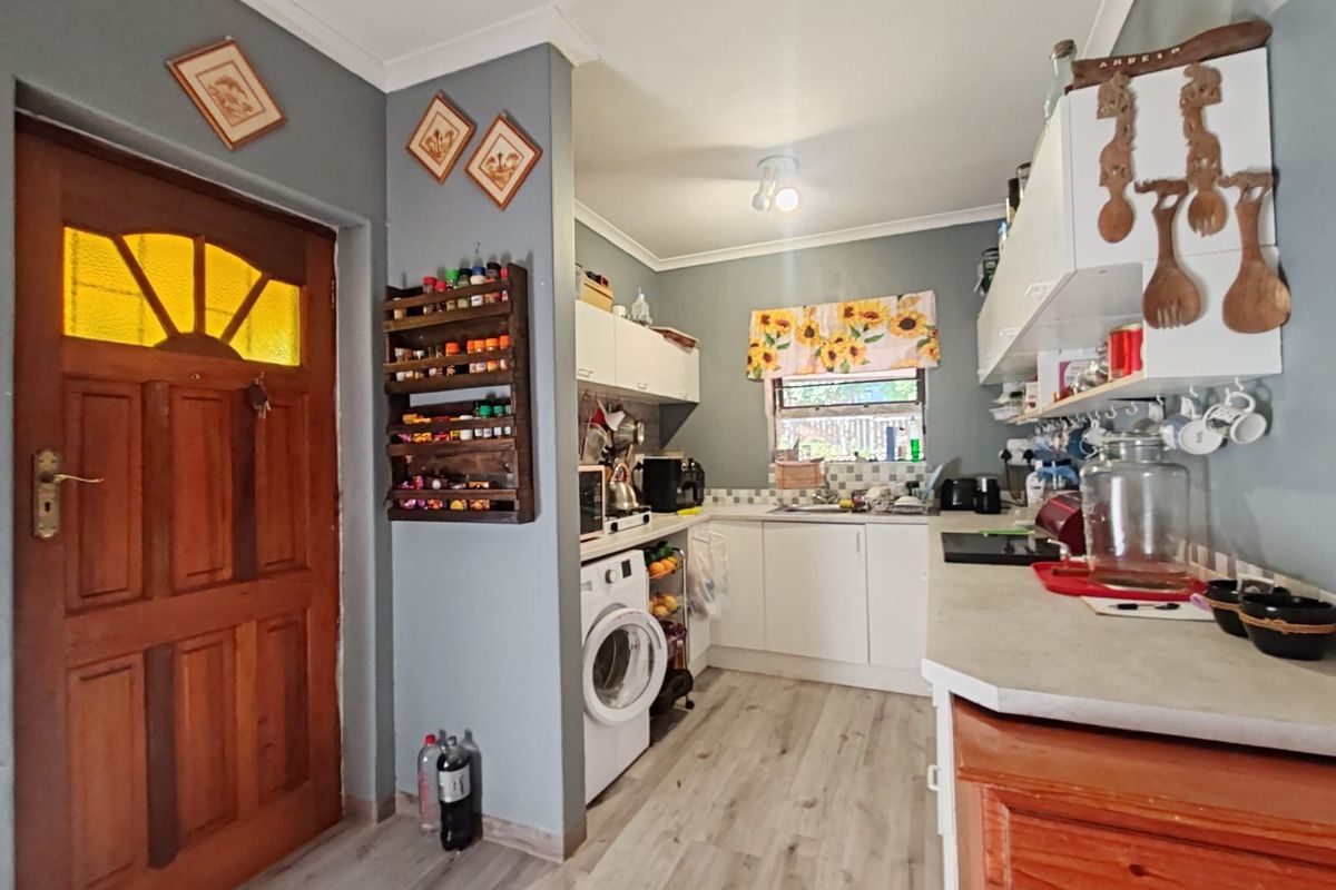 A functional kitchen featuring white cabinetry, laminate countertops, integrated laundry plumbing, and wood-look flooring, providing a practical workspace.