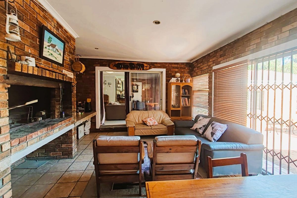 Spacious indoor entertainment area featuring a large built-in brick fireplace, tiled flooring, and sliding glass doors leading to the exterior.