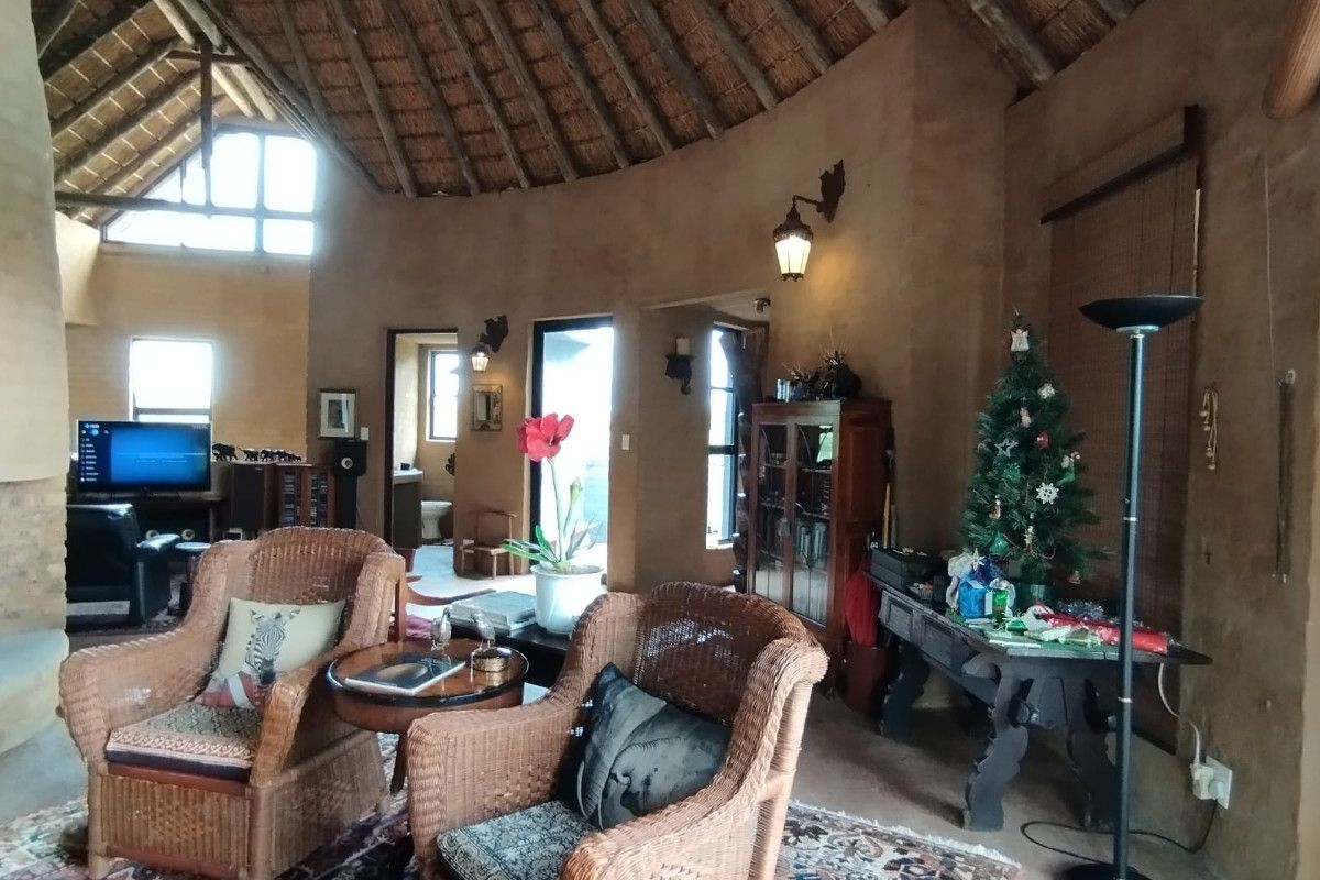 A spacious living area featuring a high vaulted thatched roof, exposed timber beams, and rustic textured walls, creating a unique architectural character.