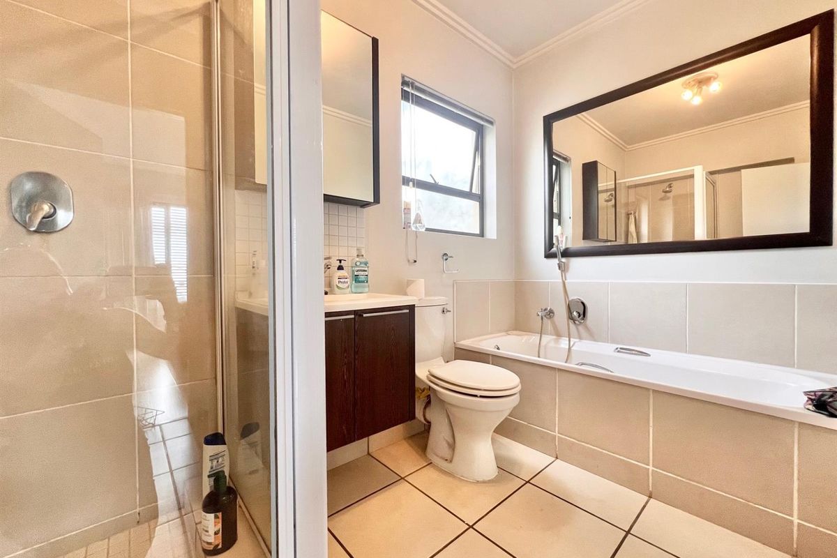 A well-maintained bathroom featuring a separate shower enclosure, bathtub, vanity cabinet, and neutral wall and floor tiling.