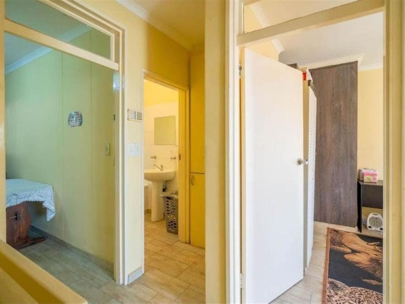 A functional hallway connecting multiple rooms, featuring tiled flooring and access to a bathroom with a pedestal basin.