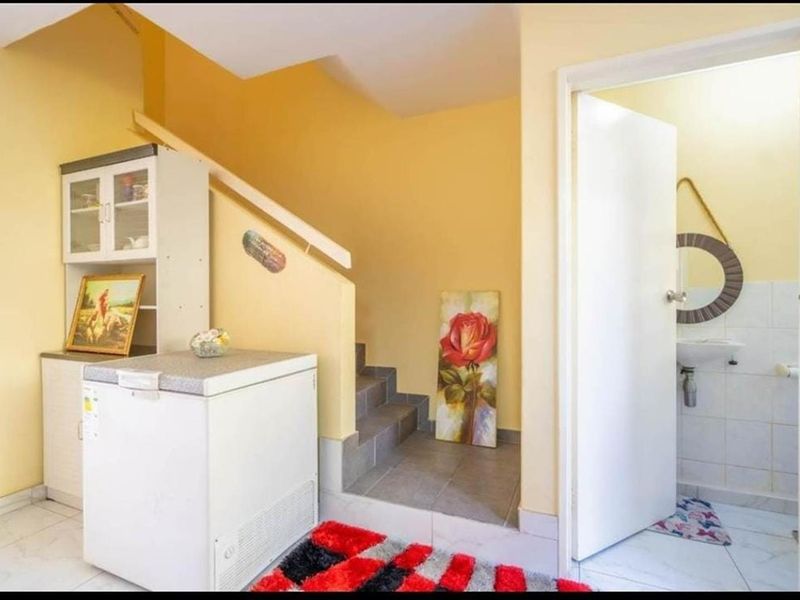 A functional hallway area featuring a staircase with a handrail, tiled flooring, and direct access to an adjacent bathroom.