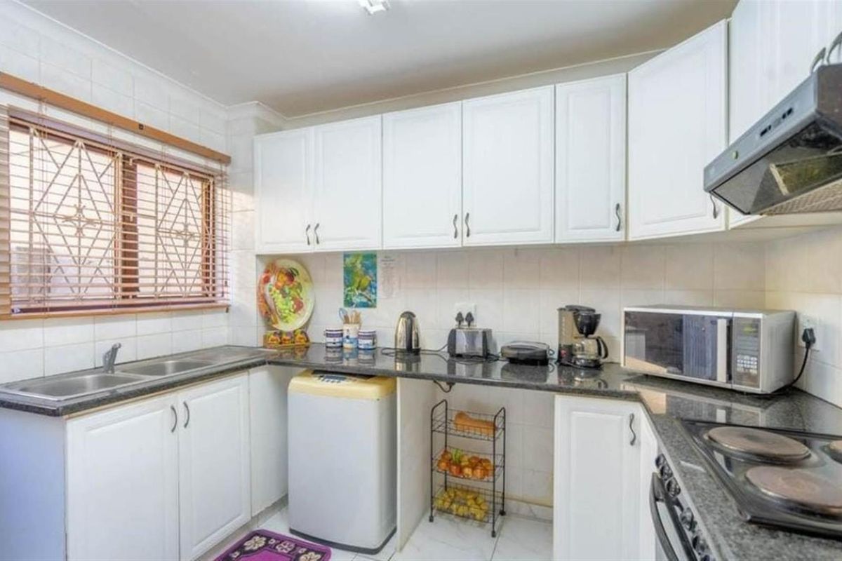 A functional kitchen featuring white cabinetry, granite countertops, a tiled backsplash, and built-in cooking appliances, offering a clean and practical workspace.