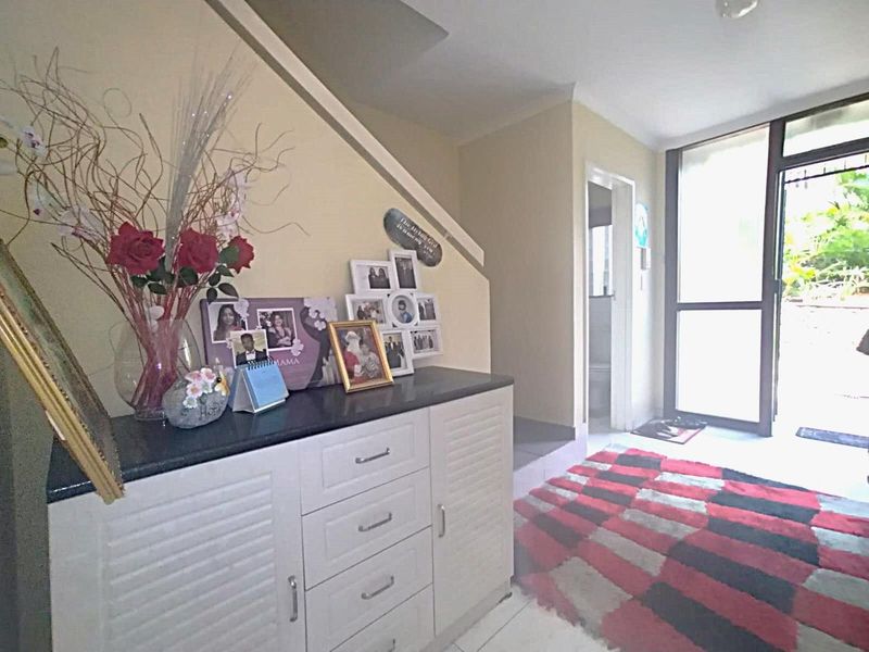 An entry area featuring tiled flooring, a staircase, and a glass panel door providing natural light and access to the exterior.