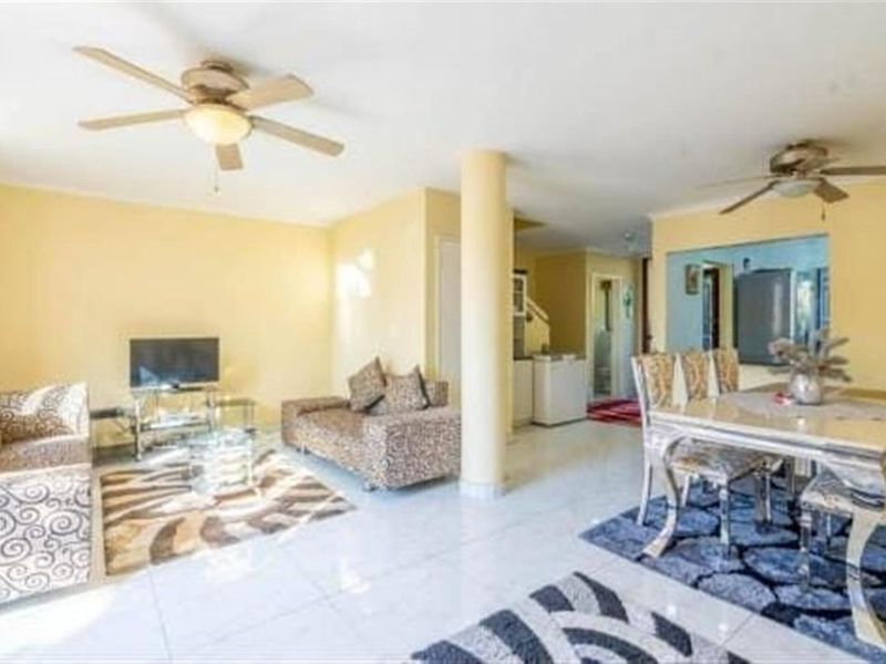Open-plan living and dining area featuring tiled flooring, a structural column, and ceiling fans, providing a functional layout for daily living.