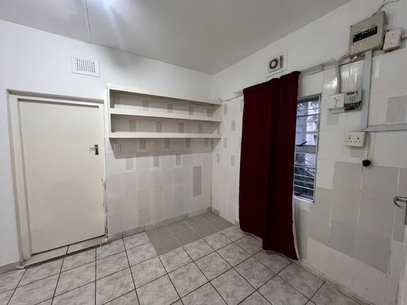 A functional utility or laundry space featuring tiled walls, built-in shelving, and direct access to an exterior door.