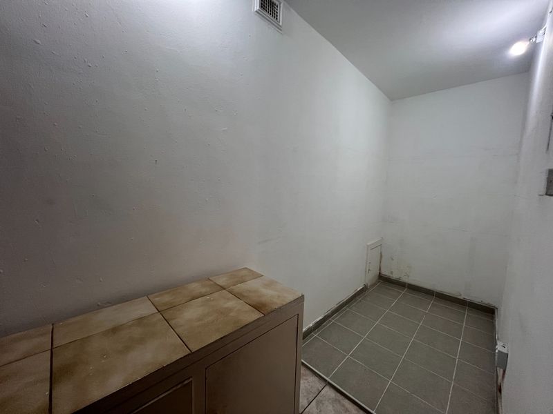 A small utility or laundry space featuring tiled flooring and a built-in tiled counter surface.
