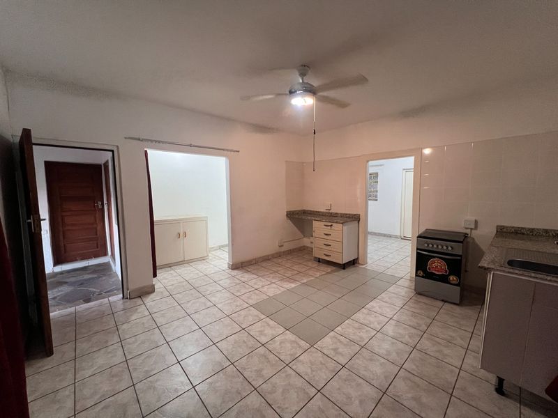 A functional kitchen area featuring tiled flooring, built-in cabinetry, a stove, and a ceiling fan, providing a practical layout for daily meal preparation.