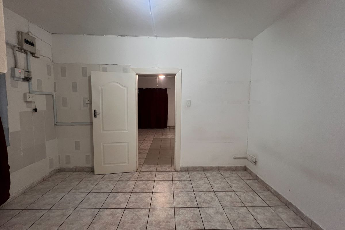 An empty, functional room featuring tiled flooring and exposed electrical infrastructure, providing a blank canvas for renovation or interior design updates.