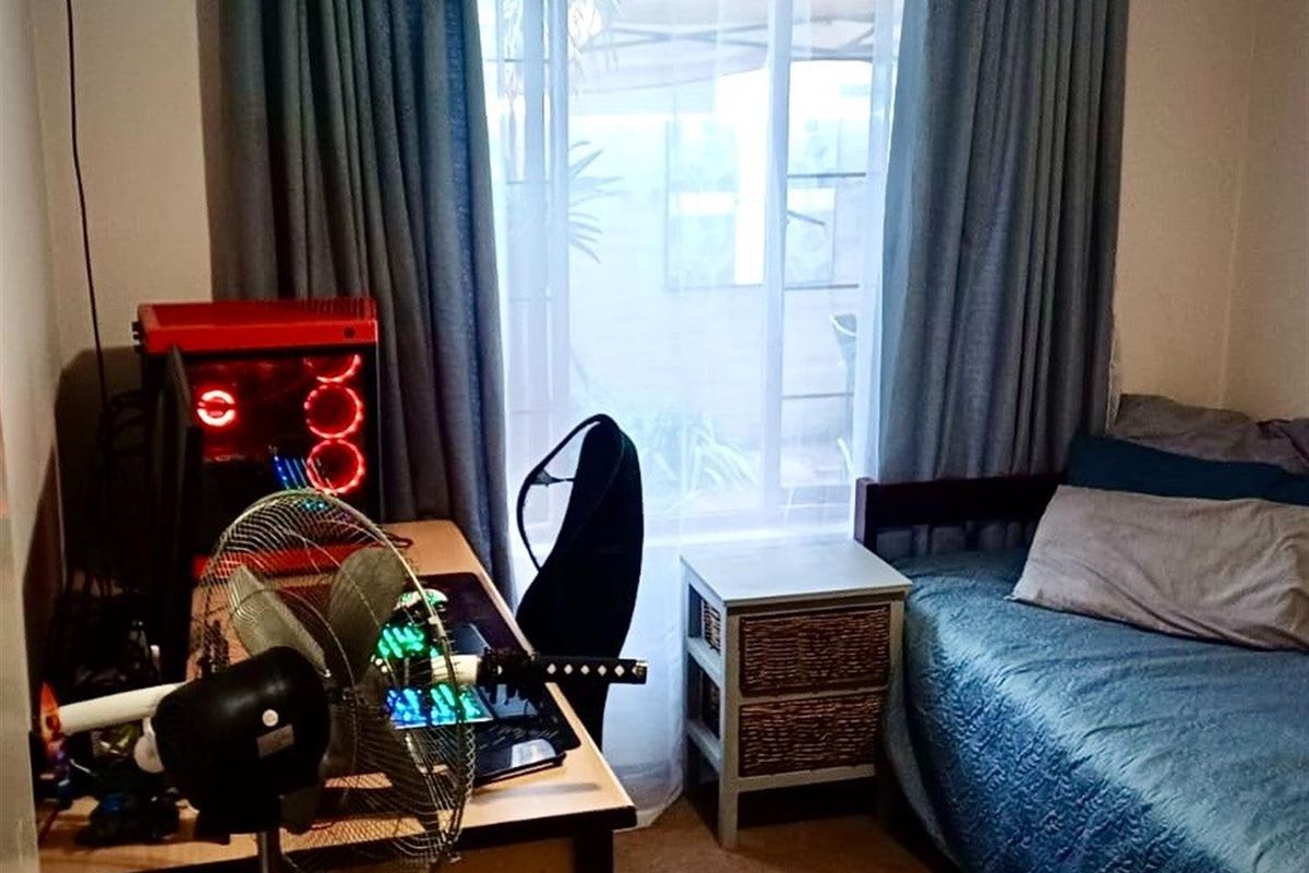 A functional bedroom featuring a large window with curtains, providing natural light and access to the exterior.