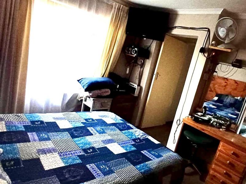 A bedroom featuring an attached en-suite bathroom area with a pedestal basin, large window, and visible electrical wiring.