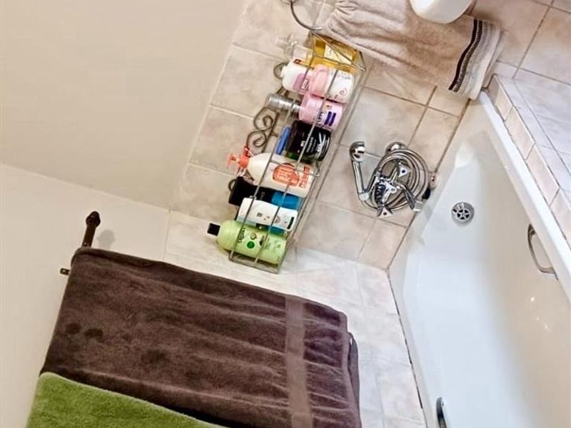 A functional bathroom featuring a white pedestal basin, a bathtub with chrome mixer tap, and tiled wall finishes.
