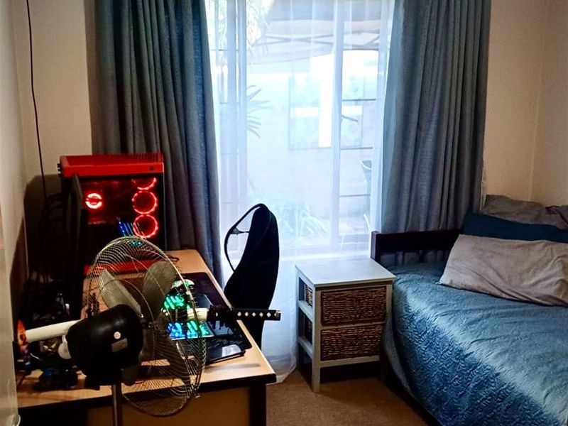 A functional bedroom featuring a large window with curtains, providing natural light and access to the exterior.