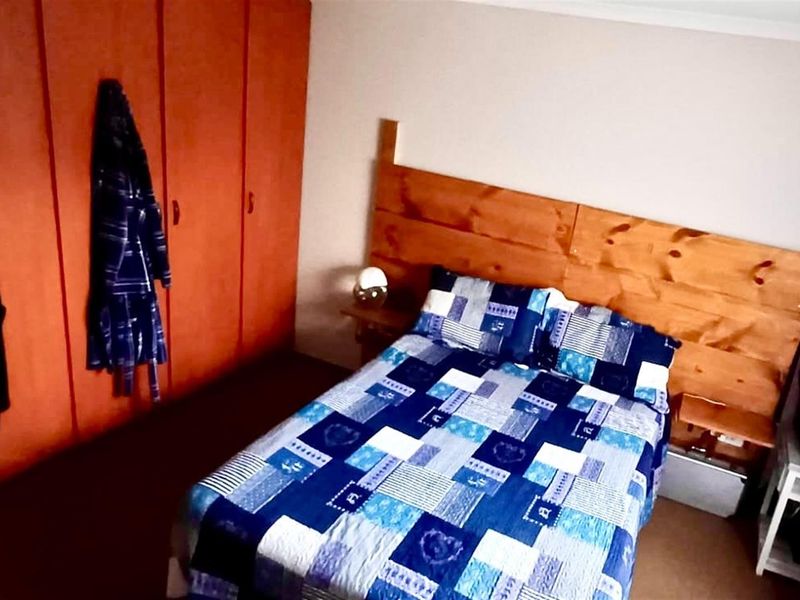 A bedroom featuring built-in wooden cupboards and a wooden headboard.