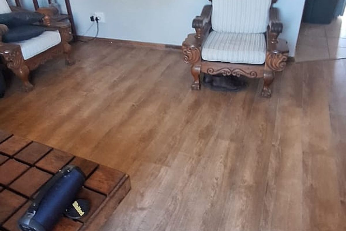A living room area featuring wood-look laminate flooring and neutral wall finishes, providing a clean and functional space.