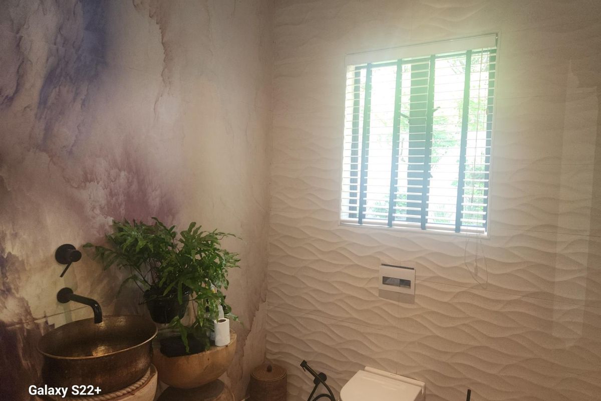 A modern bathroom featuring a unique wall-mounted basin, wall-hung toilet with concealed cistern, and textured feature wall tiles.