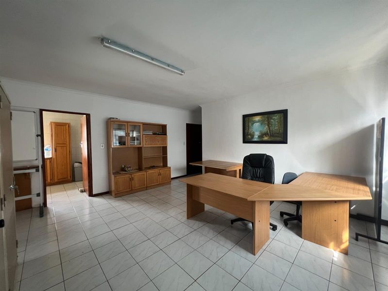 A functional office space featuring ceramic tiled flooring, a fluorescent light fixture, and built-in wooden storage cabinetry.