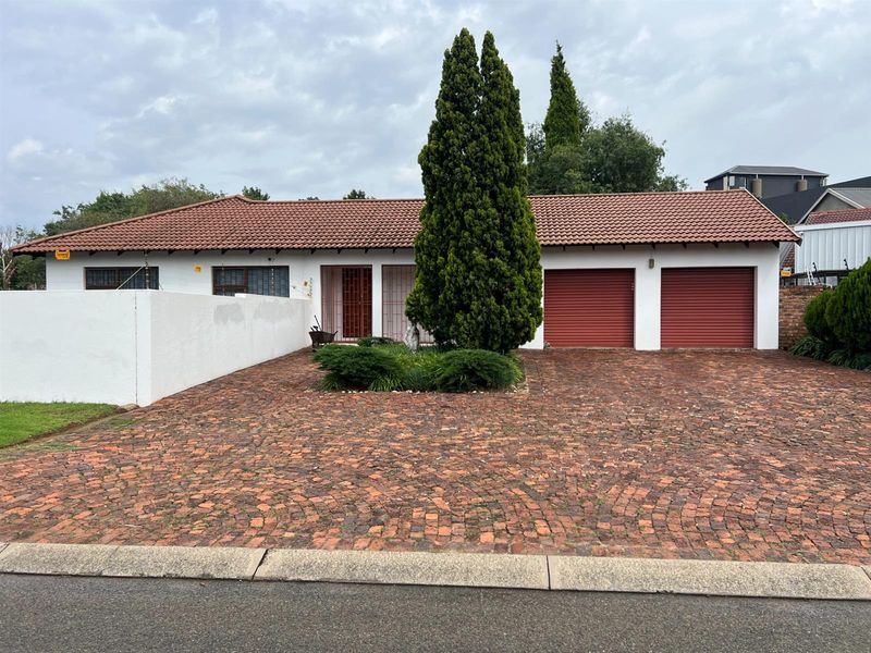 Front view of the office property featuring a double garage, brick paved driveway, and secure perimeter walling.