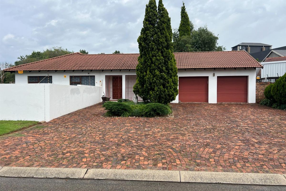Front view of the office property featuring a double garage, brick paved driveway, and secure perimeter walling.
