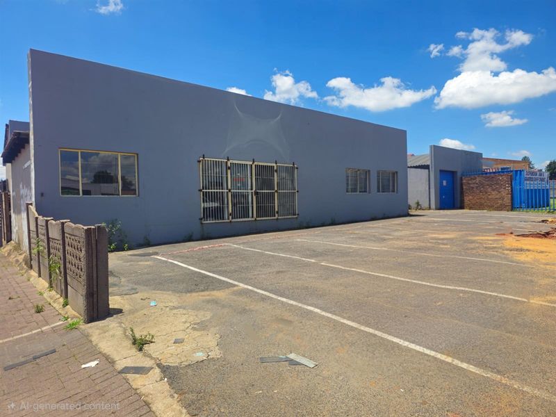 Commercial property exterior featuring a paved parking area, security-barred windows, and a painted facade with visible surface wear.